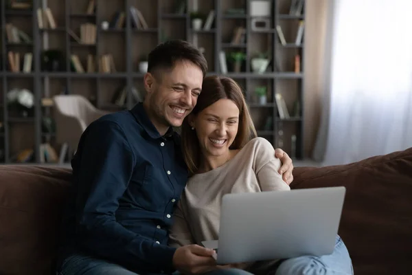 Smiling man and woman use computer relaxing at home — Stockfoto
