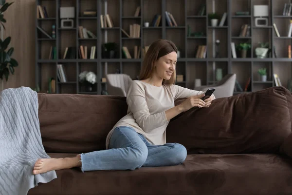 Felice giovane donna rilassarsi a casa utilizzando il cellulare — Foto Stock