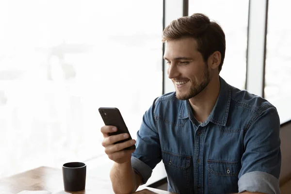 Sorridente gioioso giovane utilizzando il cellulare. — Foto Stock