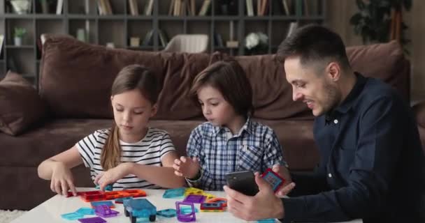 Baba küçük oğlu ve kızı ile oynamak manyetik inşaat seti — Stok video