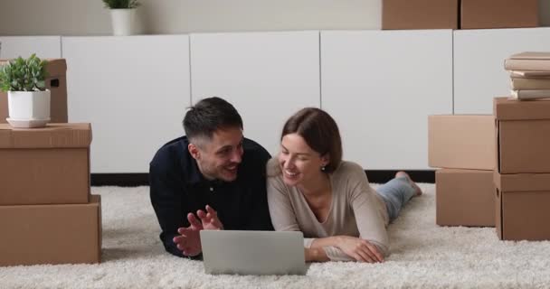 Jeune couple se détendre sur le plancher utilisation ordinateur portable au jour de la réinstallation — Video