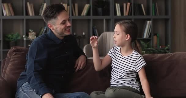 Hijita y padre hablando se sientan en el sofá en casa — Vídeo de stock