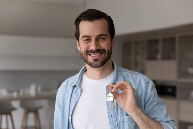 Elinde anahtar olan gülümseyen bir adamın portresi.