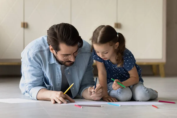 Vårdande far med bedårande liten dotter ritning, sitter på golvet — Stockfoto