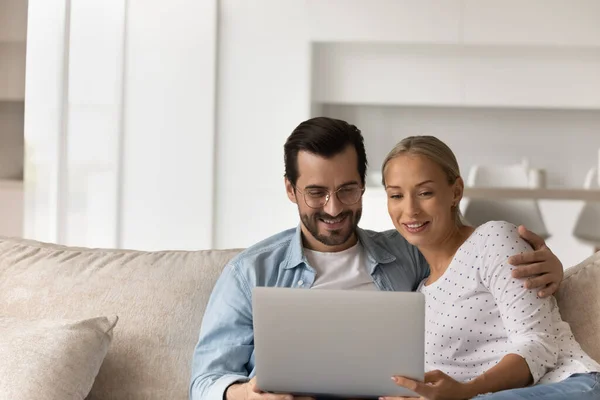 Glückliches junges Paar entspannt sich mit Laptop auf Couch — Stockfoto