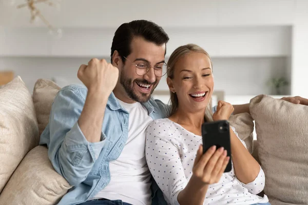 Eccitato giovane coppia guardando lo schermo del telefono insieme, celebrando il successo — Foto Stock