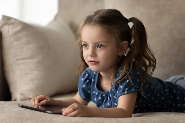 Close up little 7s girl relaxing on couch with tablet — Stock Photo, Image