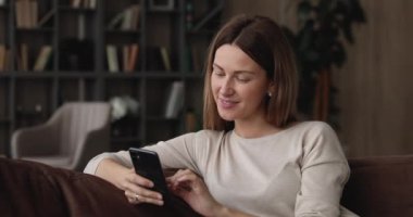 Kanepede oturan kadın akıllı telefon kullanarak arkadaşına mesaj atıyor.