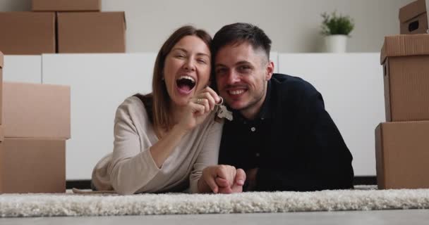 Couple lying on floor holding keys looking at camera — Stock Video