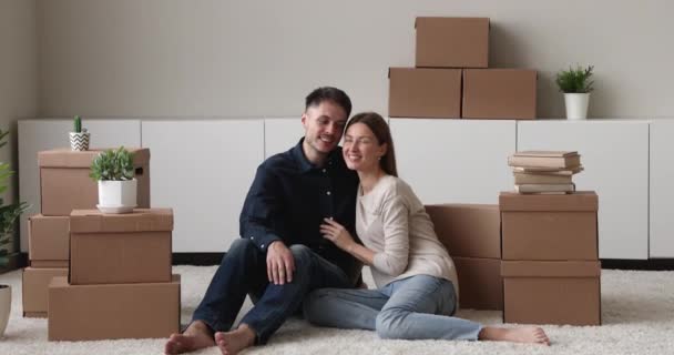 Пара сидить на підлозі, відпочиваючи в день переселення поблизу коробок — стокове відео