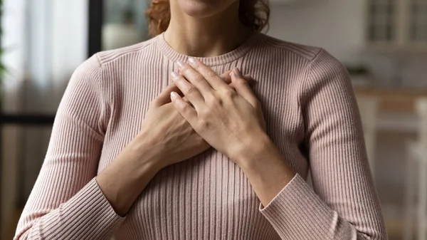 Young woman holding folded hands on chest heart. — Stock Photo, Image