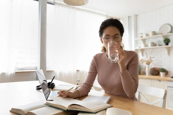 Concentrated young woman drinking glass ow water, reading book. — Stock Photo, Image