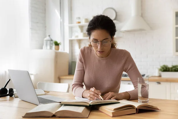 Συγκεντρωμένη νεαρή γυναίκα σε eyewear ανάγνωση εκπαιδευτικό βιβλίο. — Φωτογραφία Αρχείου