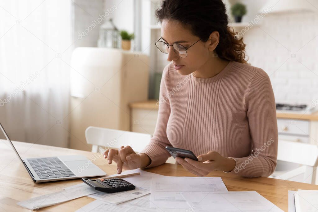 Concentrated millennial woman paying bills in mobile app.
