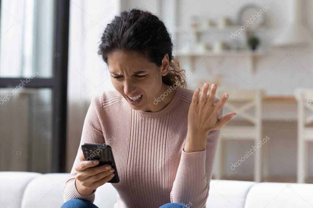 Frustrated young woman looking at cellphone screen.