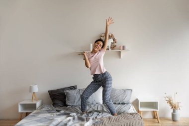 Mutlu genç İspanyol kadın yatakta dans ediyor..