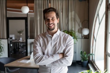 Kollarını kavuşturmuş gülümseyen iş adamının portresi.