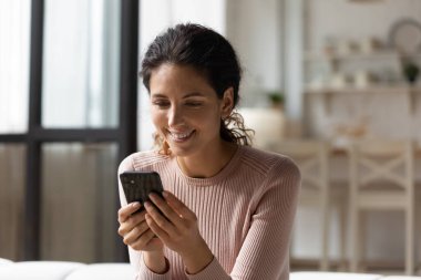 Gülümseyen bin yıllık İspanyol kadın evde akıllı telefon kullanıyor..