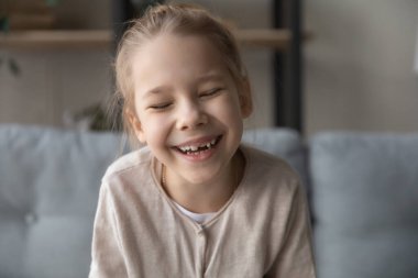 Çok neşeli küçük bir kız. Gözleri kapalı gülüyor. Video aracılığıyla iletişim kuruyor.