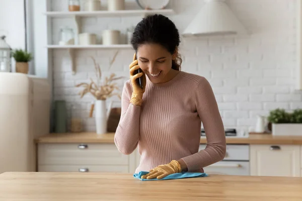 Счастливая молодая домохозяйка снимает на мобильный телефон во время уборки кухни. — стоковое фото