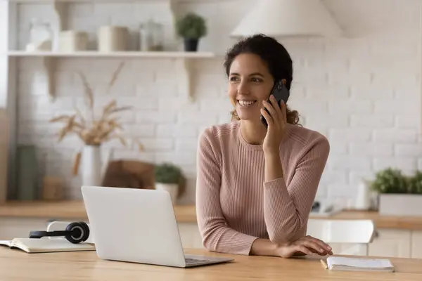 Happy young businesswoman holding cellphone conversation, working on computer. — Stock Photo, Image