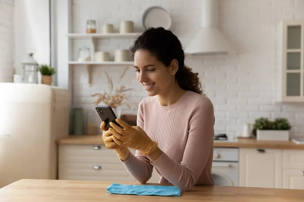 Distraído de la limpieza de la mujer joven que envía un mensaje en el teléfono inteligente. — Foto de Stock