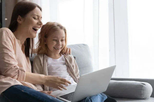 Überglückliches Schulmädchen und ihre Mutter sehen lustige Zeichentrickfilme am PC — Stockfoto