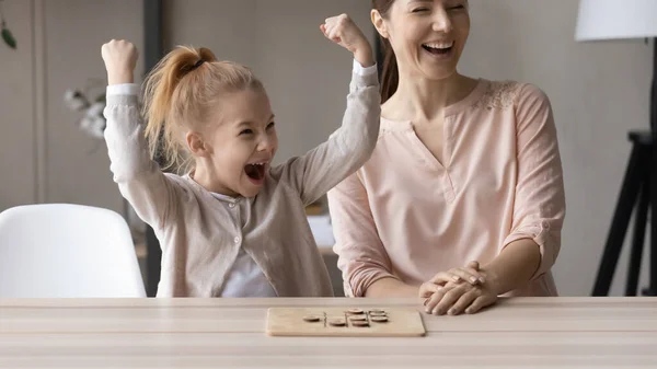 Emocionado niña pequeña hija ganar ronda de juego de mesa contra mamá — Foto de Stock