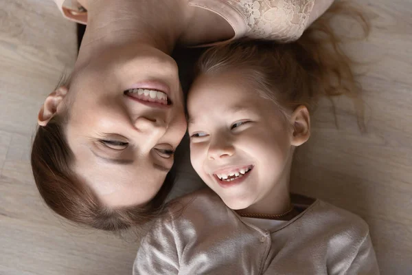 Mãe feliz e filha pré-adolescente deitada no chão quente sorrindo — Fotografia de Stock