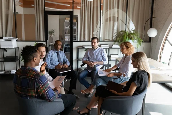 Diversos empresarios serios discutiendo estadísticas de proyectos, sentados en círculo — Foto de Stock