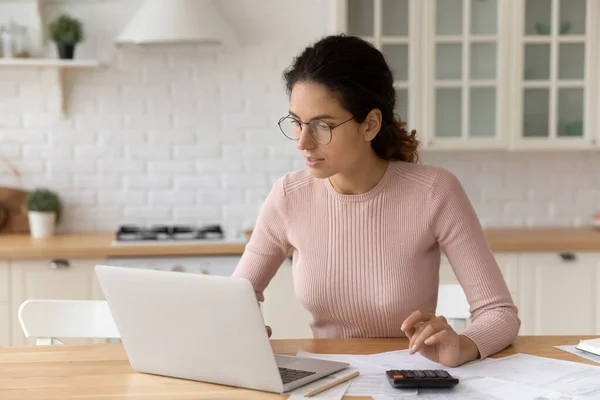 Gericht duizendjarige vrouw in bril betalen rekeningen online. — Stockfoto