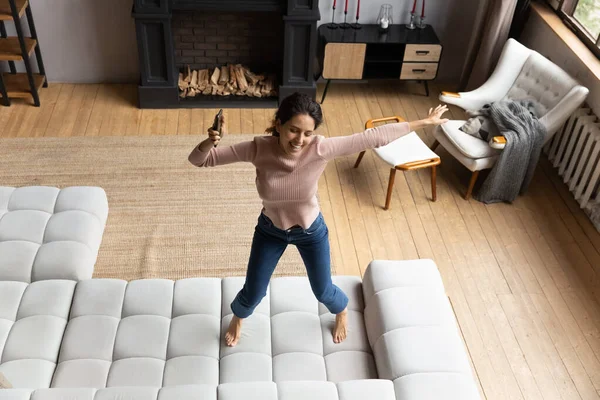 Emotionele energieke jonge Spaanse vrouw dansend op de bank. — Stockfoto