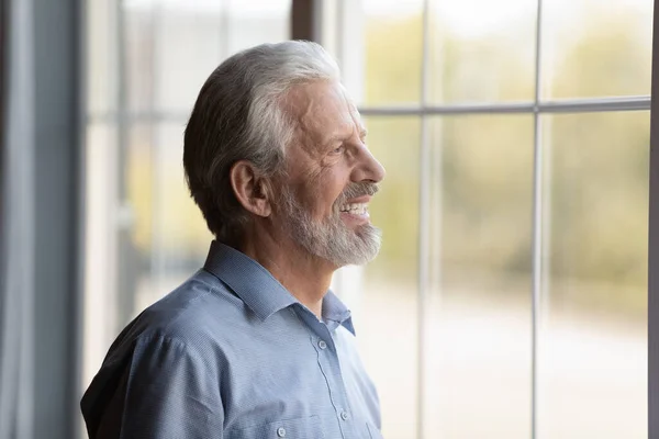 Heureux réfléchi plus âgé des années 70 homme regardant par la fenêtre — Photo