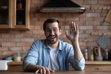 Mutlu, genç, heyecanlı, gözlüklü adam el sallıyor.