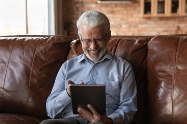 Tablet üzerinde online uygulama kullanan 70 'li yaşlarda mutlu bir emekli.
