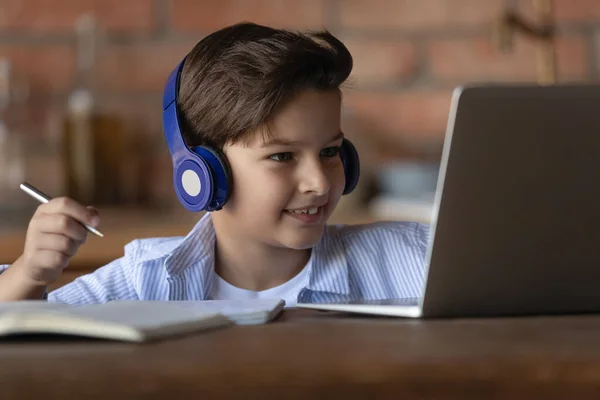 Gelukkig kind in hoofdtelefoon met behulp van laptop voor het bijwonen van virtuele klasse — Stockfoto