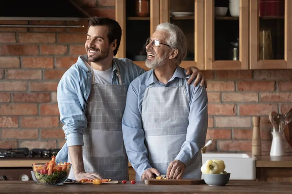 Feliz maduro 70 pai e filho crescido cozinhar refeição saudável — Fotografia de Stock