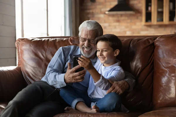 Happy preschooler boy and mature senior 70s grandpa using smartphone — Stock Photo, Image