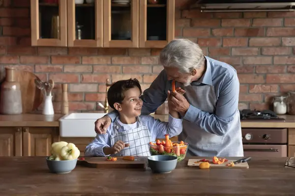 Feliz neto e avô cozinhar salada para o almoço em casa — Fotografia de Stock