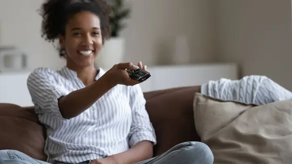 De cerca sonriente mujer afroamericana sosteniendo controlador de televisión — Foto de Stock