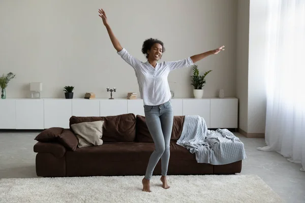 Verheugde Afro-Amerikaanse vrouw dansend in de moderne woonkamer alleen — Stockfoto