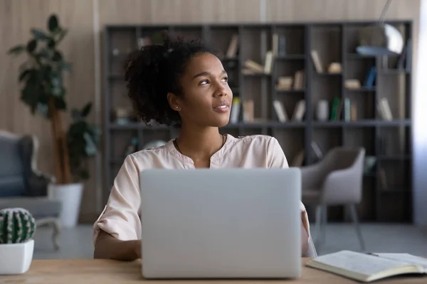 Dreamy African American woman looking to aside, distracted from laptop — Stock Photo, Image