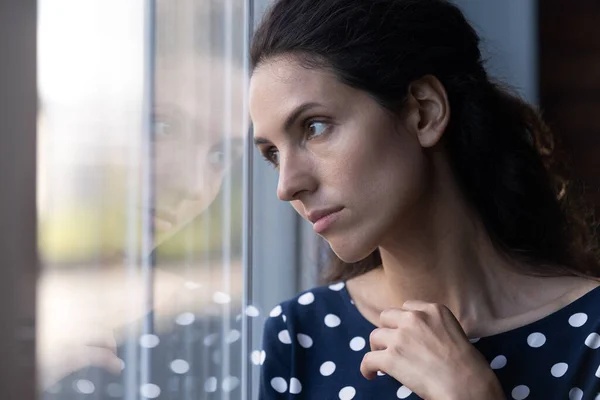 Triste mujer hispana pensativa mirando por la ventana en pensamiento profundo —  Fotos de Stock