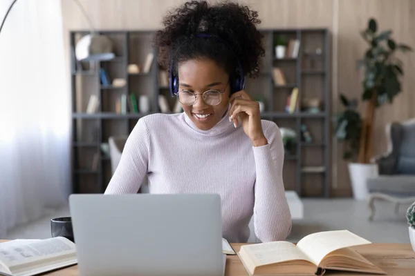 Smiling African American woman in headphones using laptop, watching webinar — Stock Photo, Image