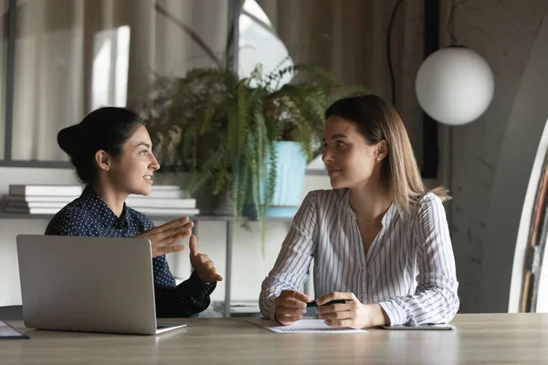 Diverse female office employees discussing project, talking at meeting table — стоковое фото