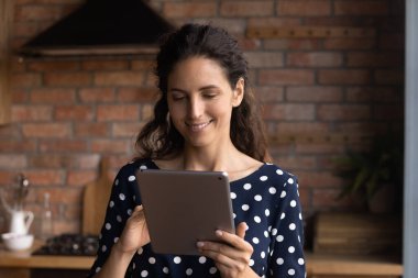 Evde bilgisayar tableti kullanan mutlu İspanyol kadın.