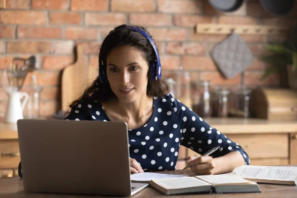 Happy focused female adult student with headphones and laptop — стоковое фото
