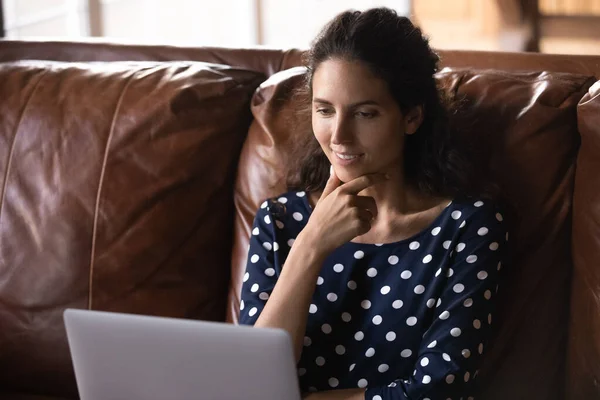 Mujer feliz relajarse en el sofá con la película en el ordenador portátil —  Fotos de Stock