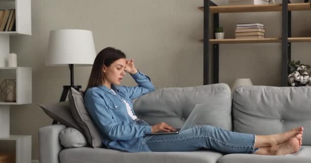 Relaxed young woman lying on cozy sofa, using computer. — стоковое видео