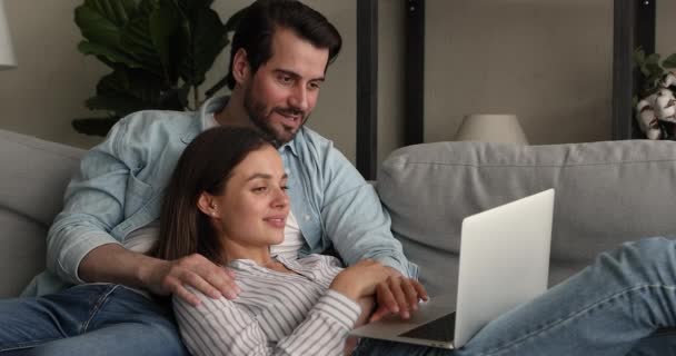 Расслабленная тысячелетняя семейная пара развлекается с помощью компьютера. — стоковое видео